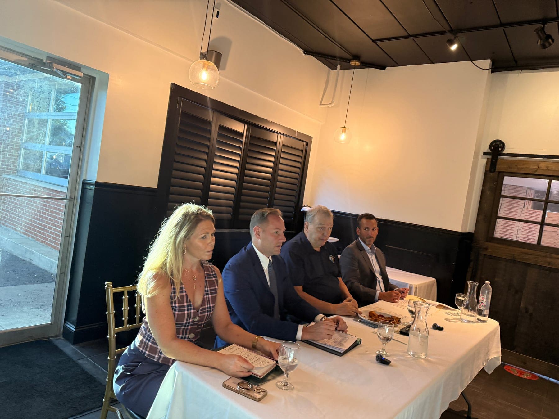 Thomas West taking notes beside speakers at a property-assessment roundtable