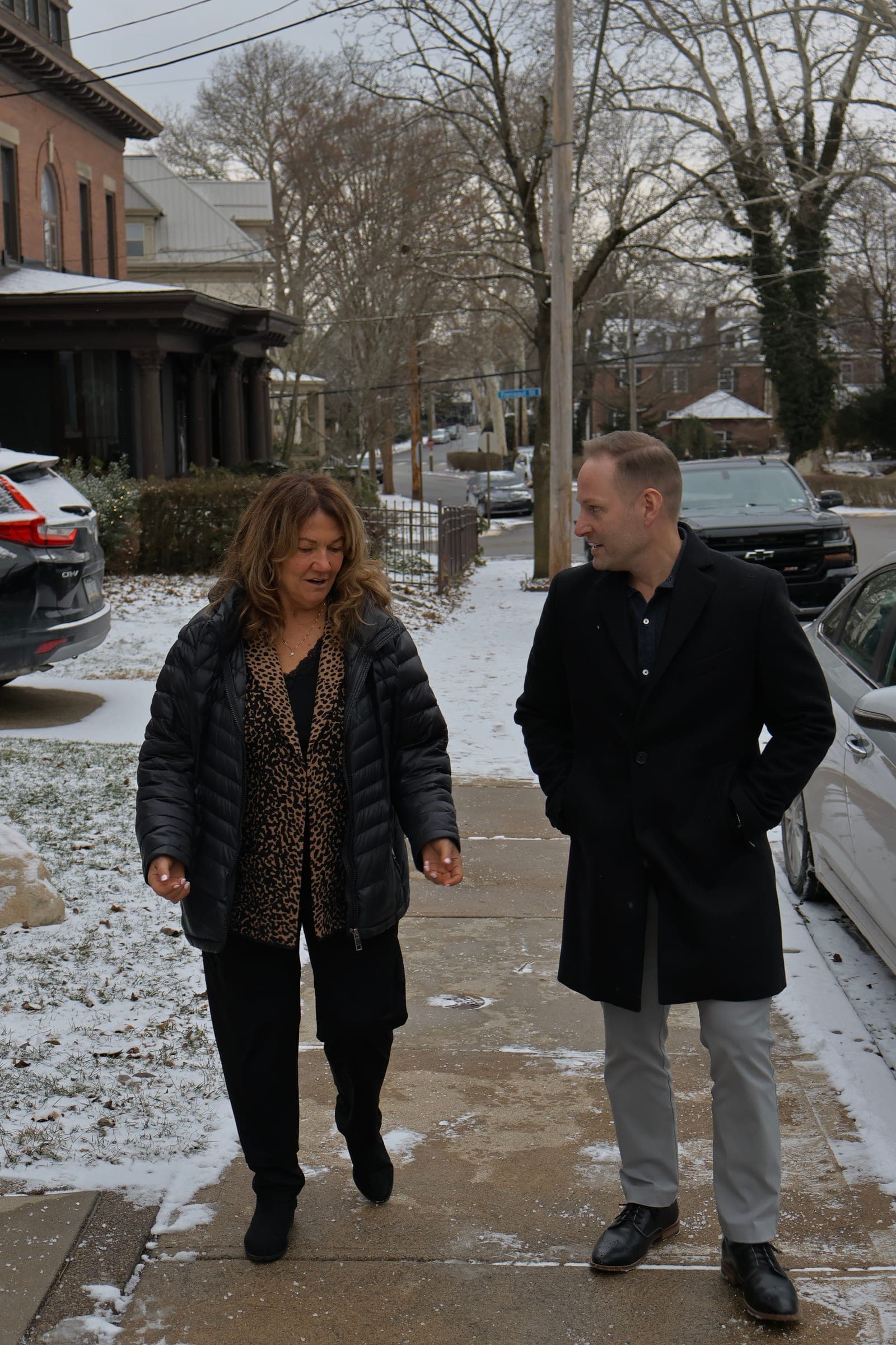Thomas West walking along a snowy neighborhood sidewalk with a resident
