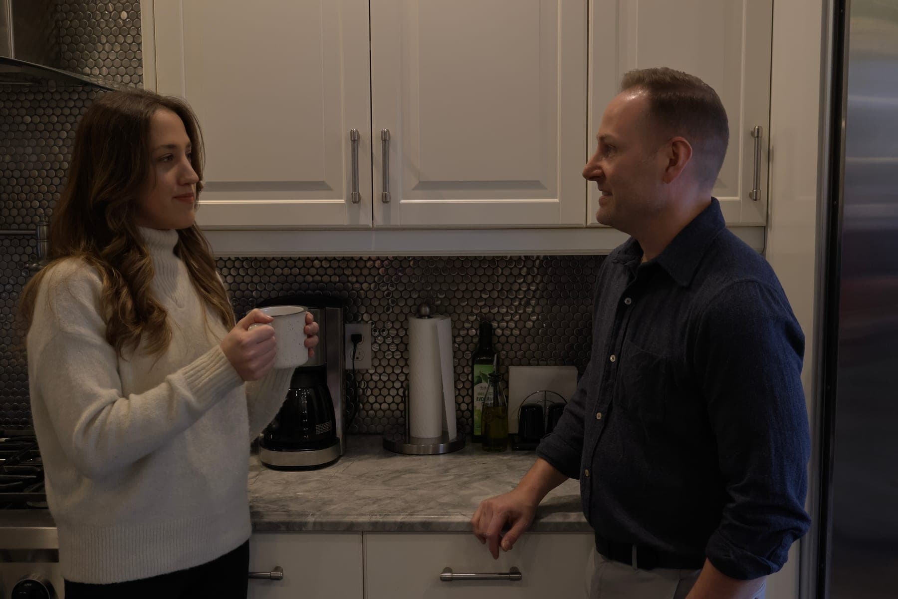 Thomas West speaking with a local resident at a kitchen table